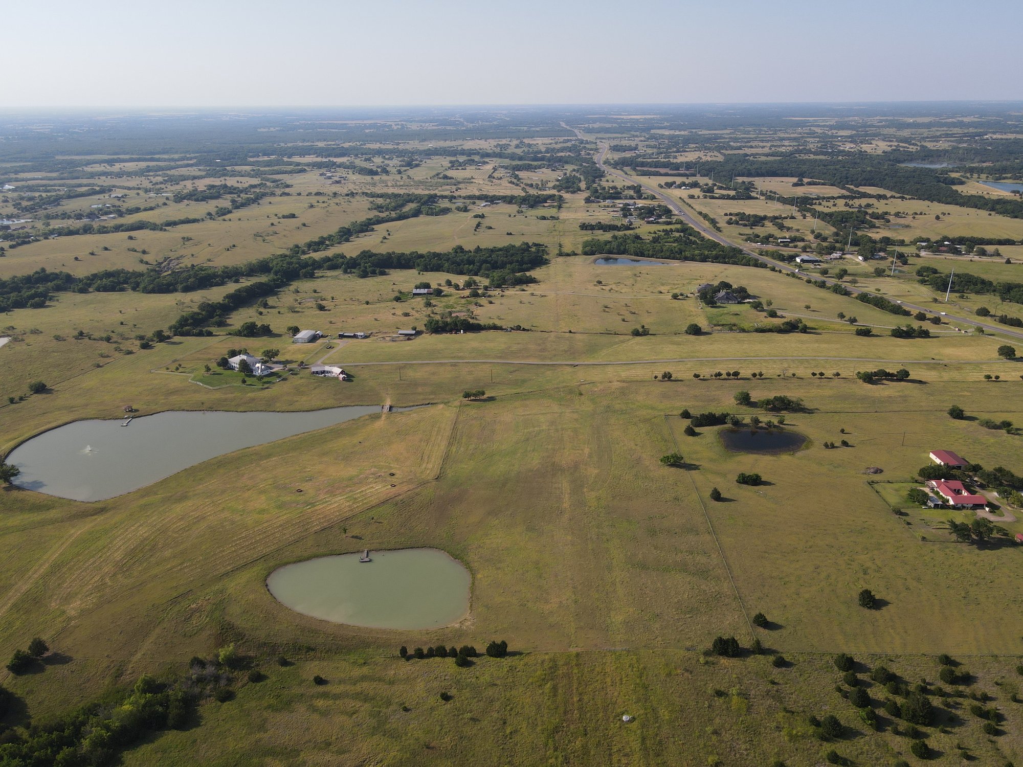 Mounger Fields aerial facing north — rural North Texas acreage with stock ponds, pasture, and state highway frontage